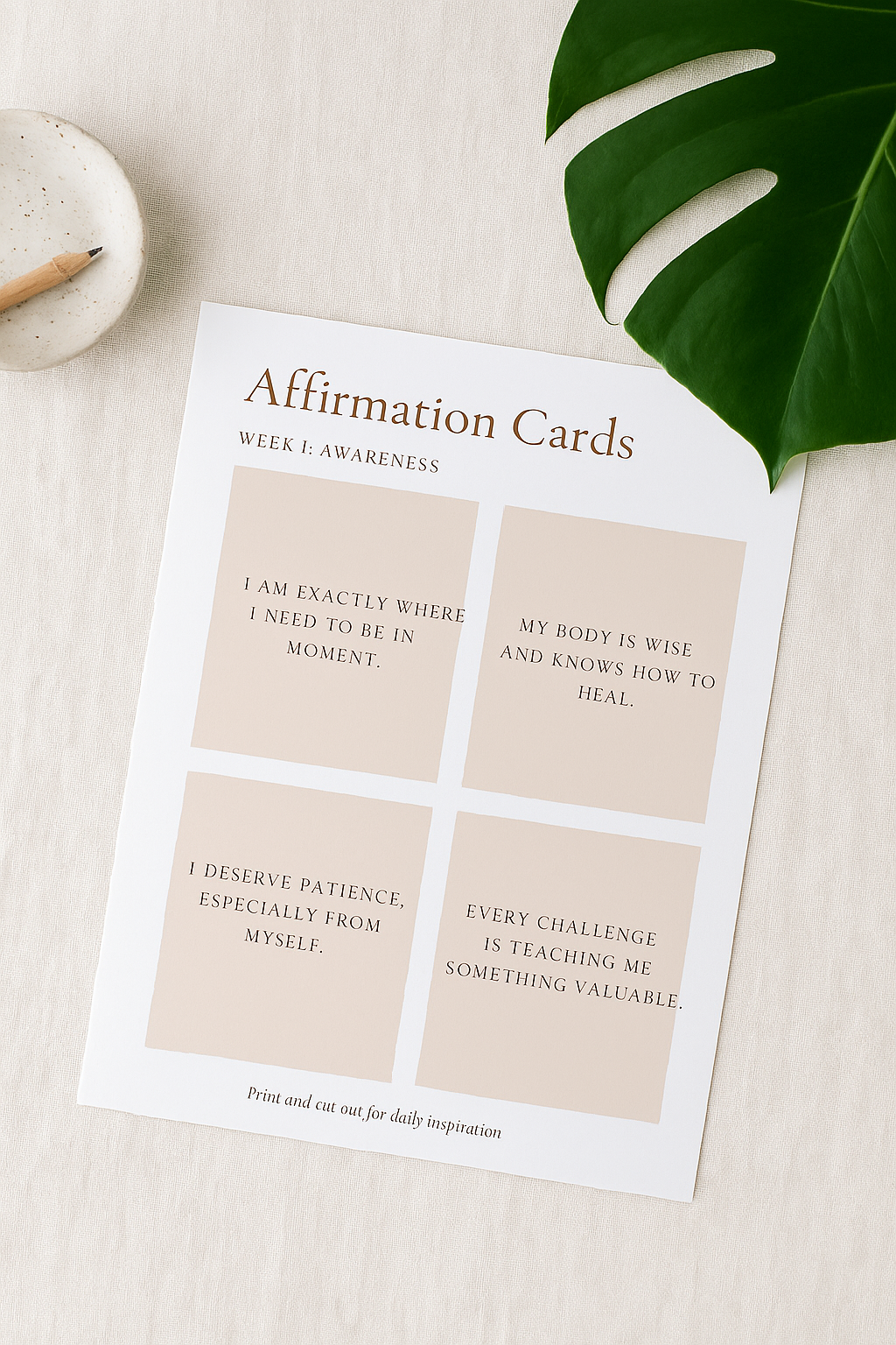 Sheet of affirmation cards on a light surface with a plant leaf