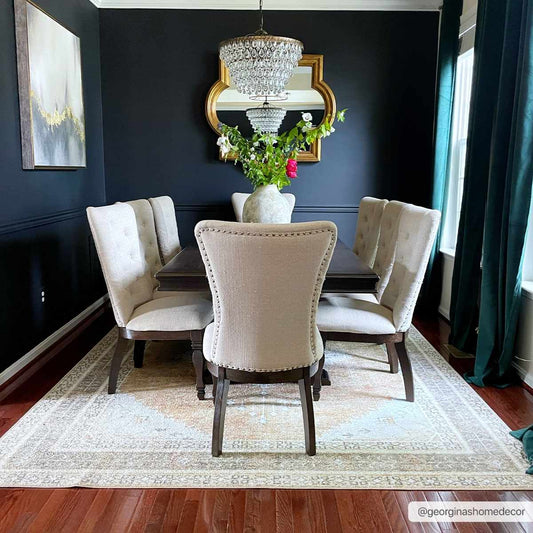 Dining room with dark walls, a chandelier, and a vase of flowers on a table.