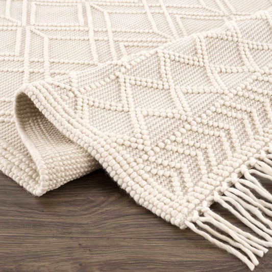 Close-up of a textured white rug with geometric pattern on a wooden floor.