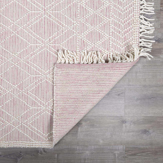 Pink and white geometric patterned rug on a wooden floor