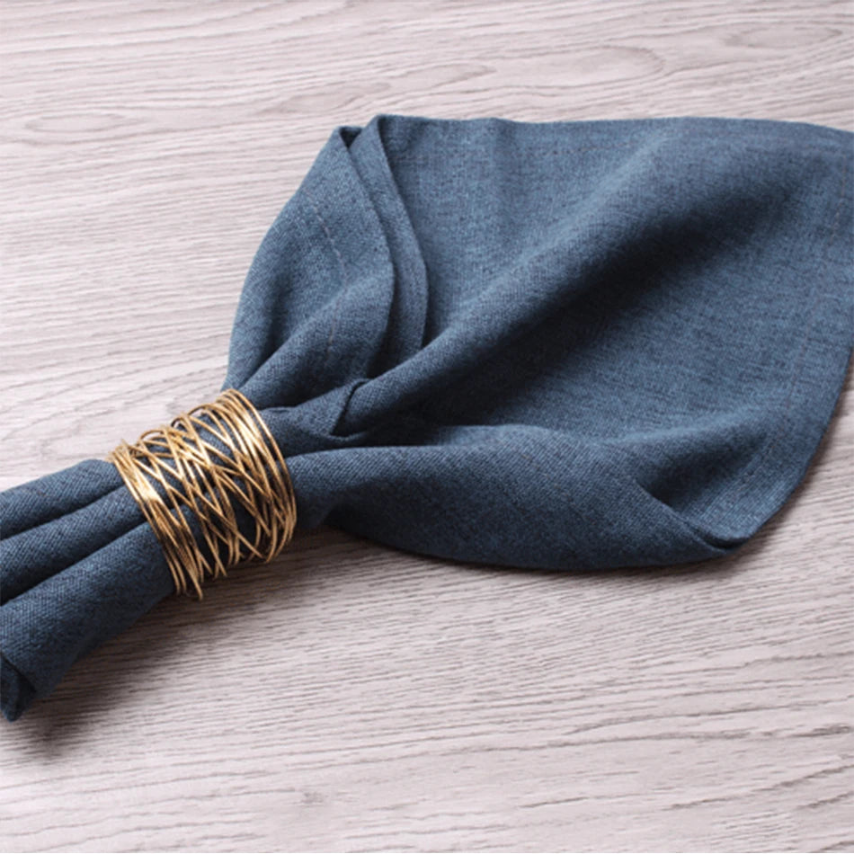 Blue napkin with a gold napkin ring on a wooden surface