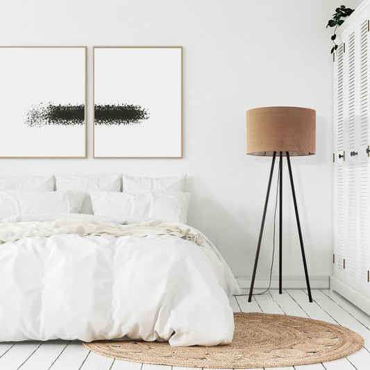 Modern bedroom with white bedding, abstract art, and a tripod lamp.