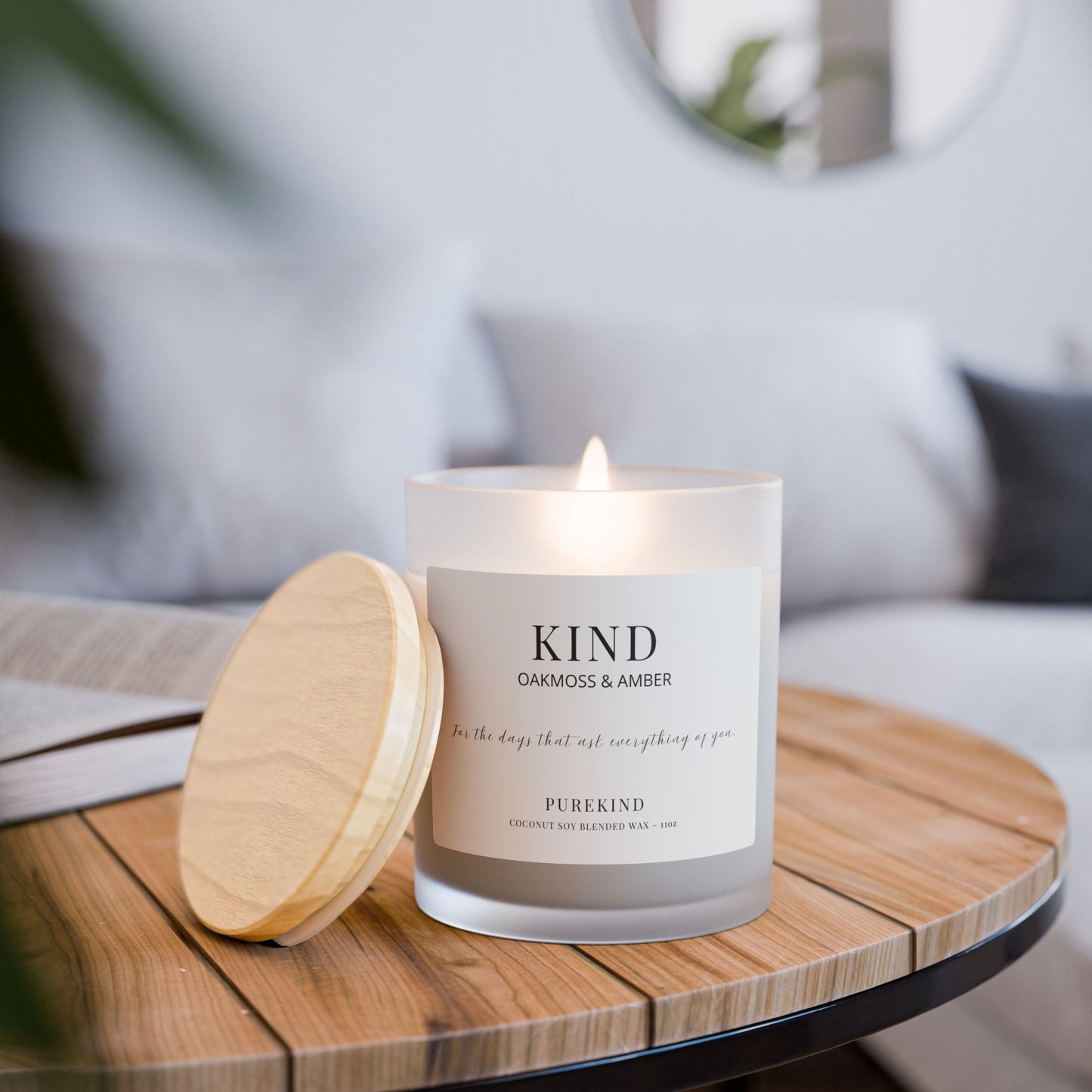 Candle labeled 'KIND' on a wooden table with a blurred background