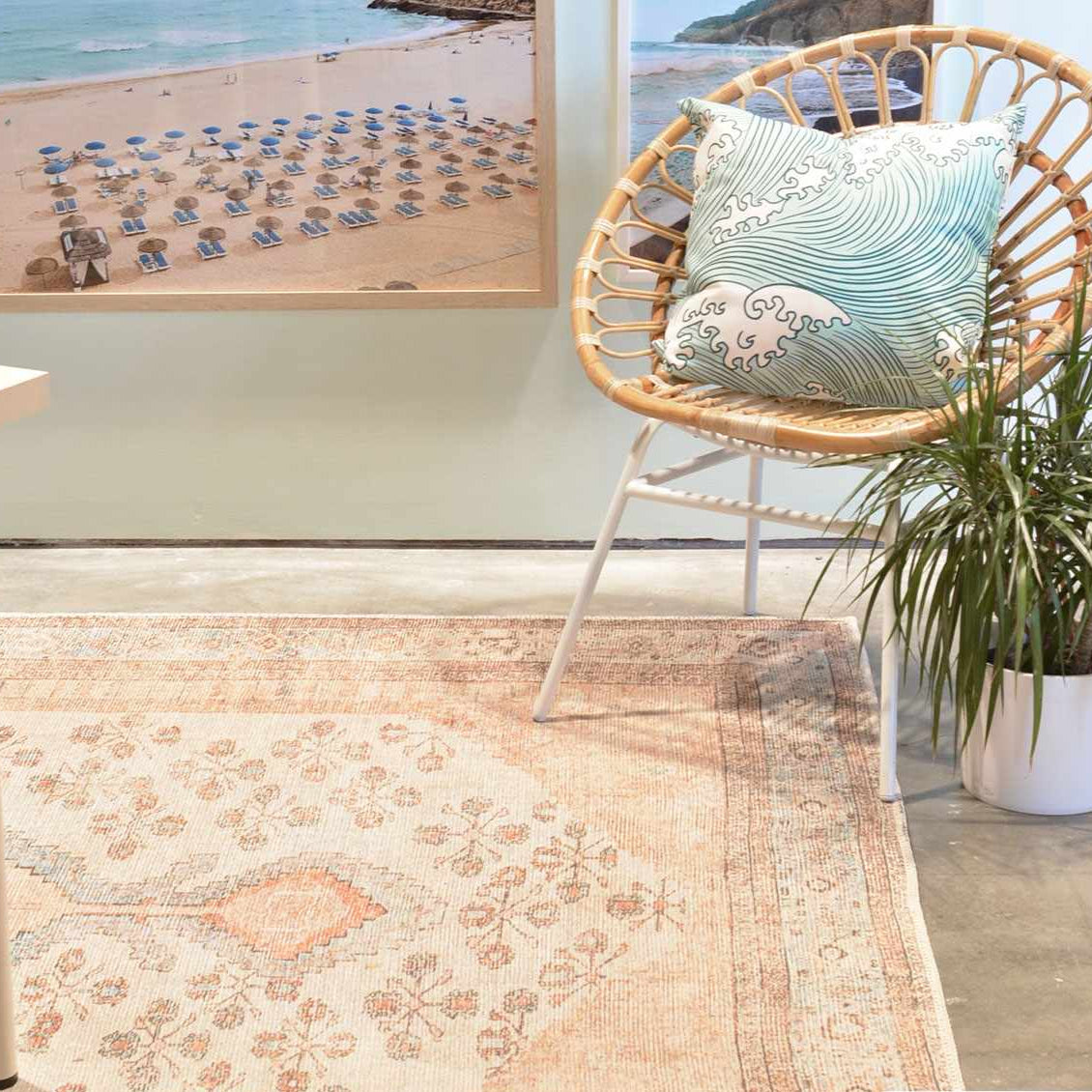 Soft pink Moora rug in coastal-inspired room with rattan chair