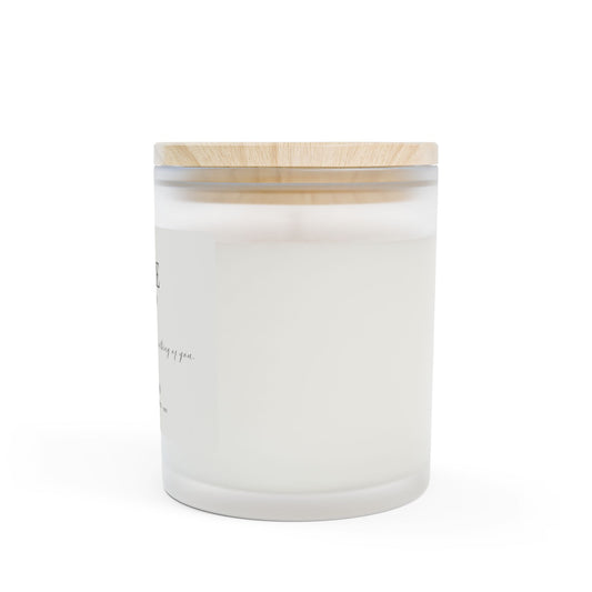 White candle in a glass jar with a wooden lid on a white background