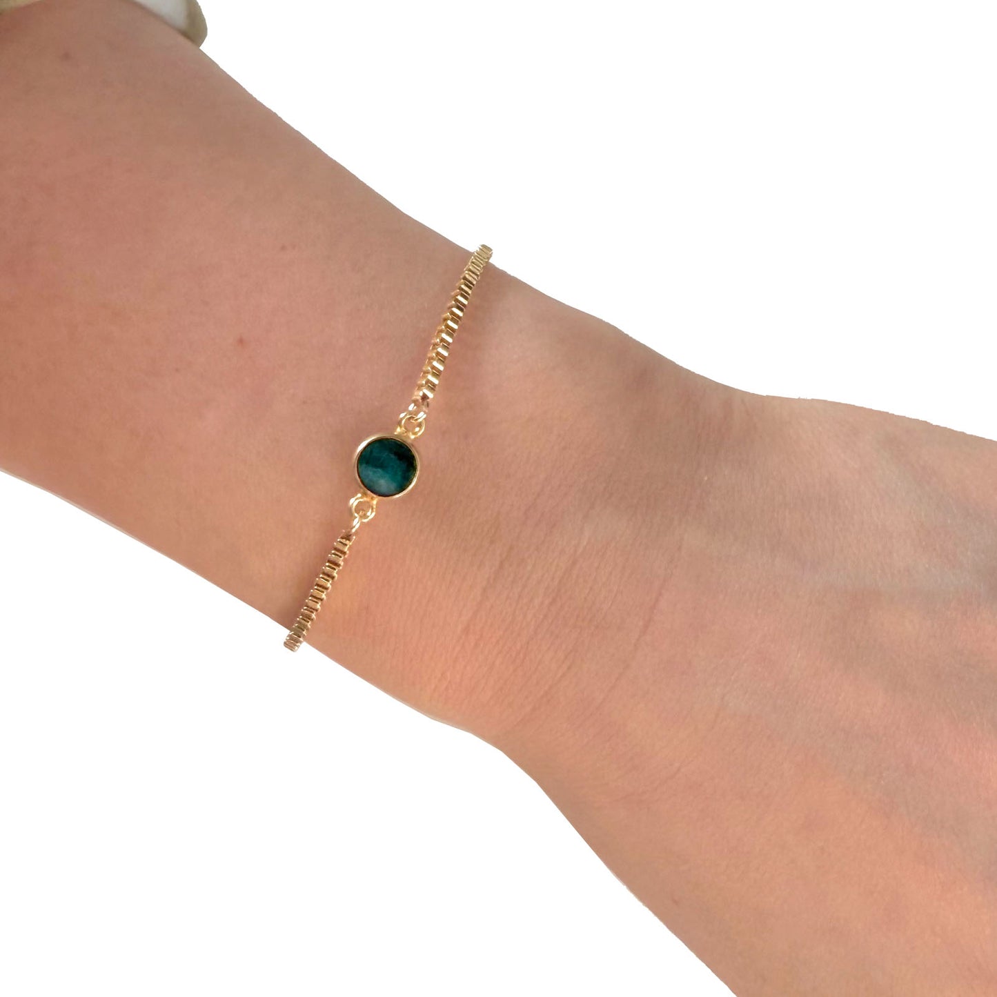 Emerald bracelet with gold chain worn on wrist