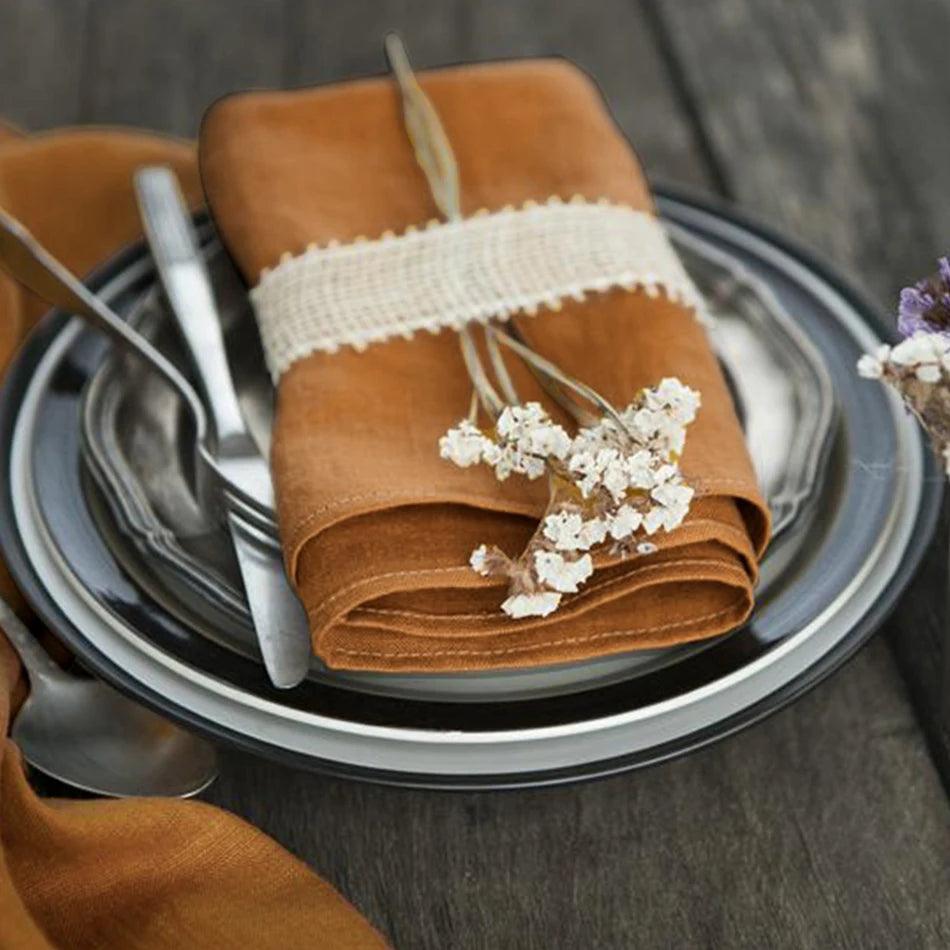 Luxury handmade linen napkins in a variety of colors, elegantly folded on a dining table.