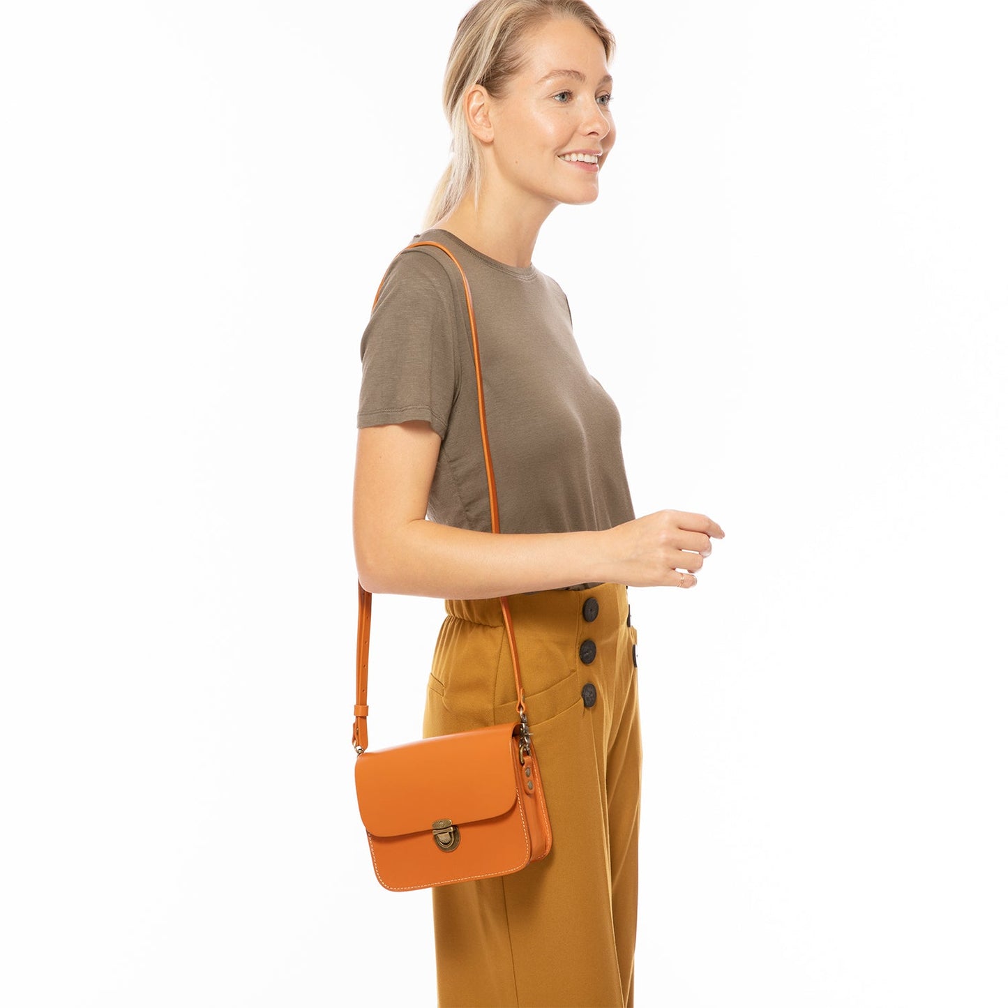Woman holding an orange crossbody bag against a white background