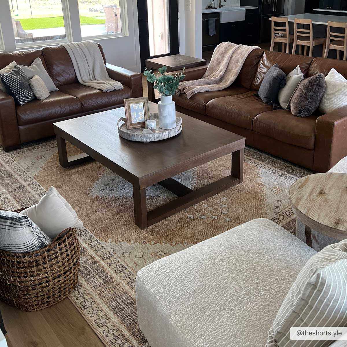 Traditional washable rug in brown and cream placed under a coffee table with leather sofas.