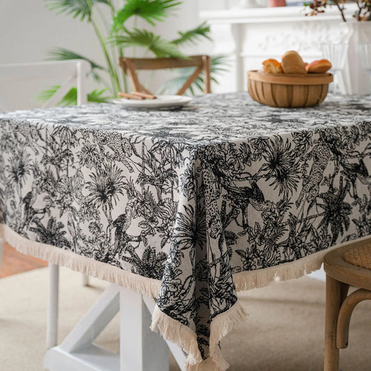 Black botanical jacquard tablecloth styled on a dining table with bowl