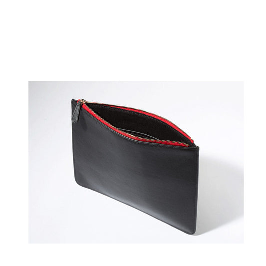 Black leather clutch iPad case with red zipper, styled for modern professionals