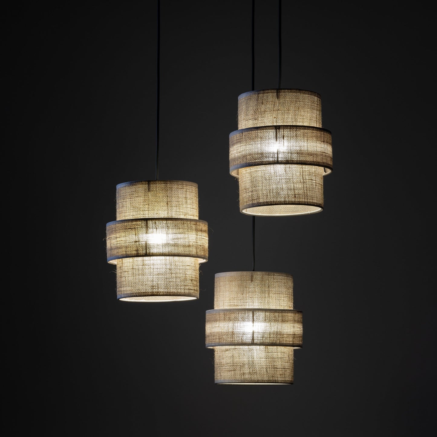 Three-light jute pendant shown in warm ambient lighting