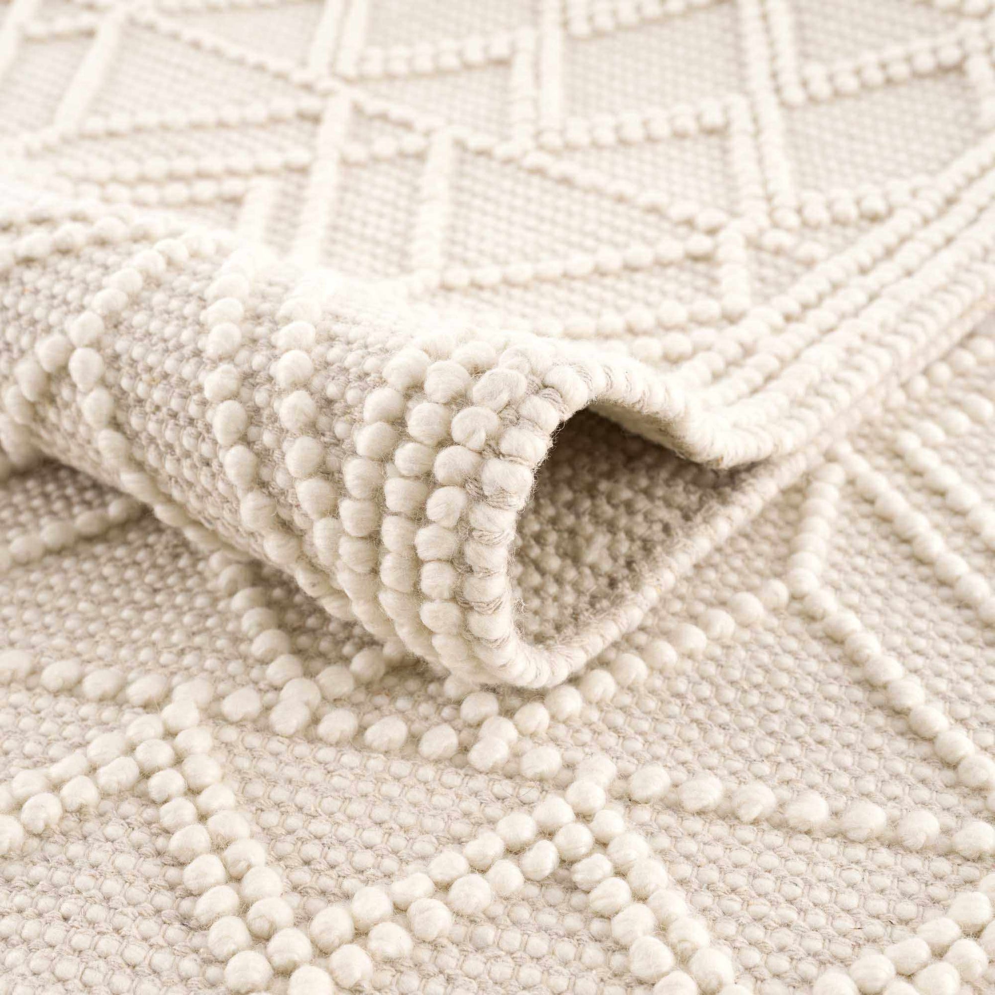 Close-up of a textured beige rug with a geometric pattern