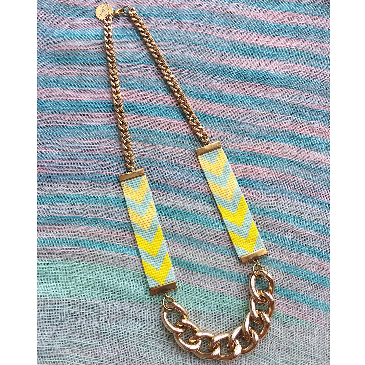 Necklace with colorful striped pendants on a striped fabric background