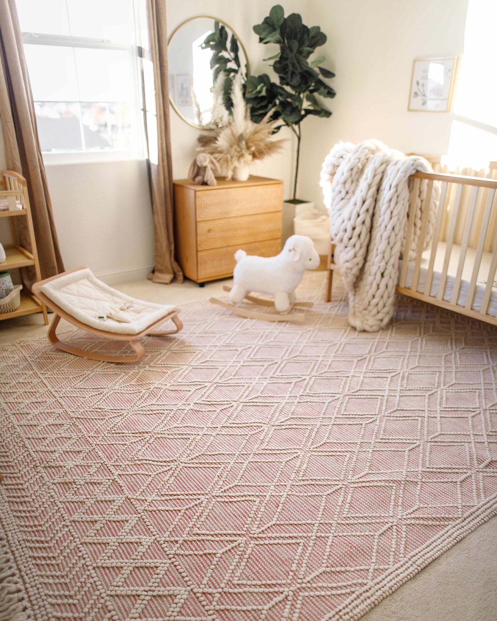 Nursery room with a geometric patterned rug, crib, and wooden furniture.