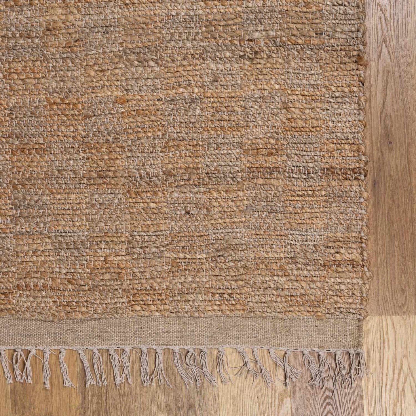 Textured brown rug with fringes on a wooden floor