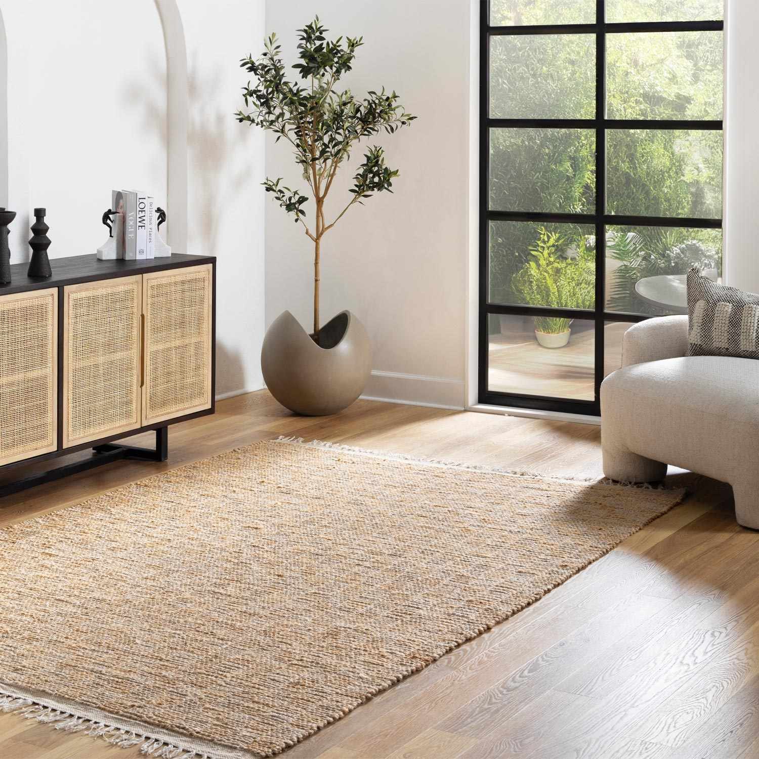 Living room with a woven rug, modern furniture, and large windows.