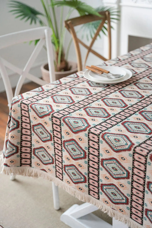 Close-up detail of woven diamond pattern in cream, rose, teal, and sand with fringe