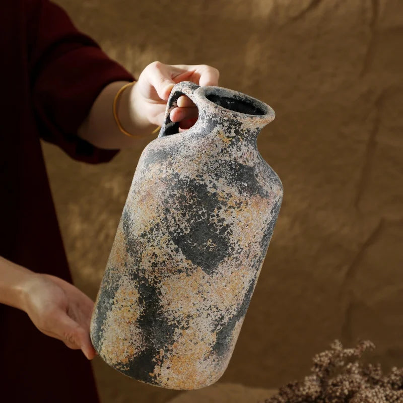 Person holding a textured ceramic vase against a warm-toned background