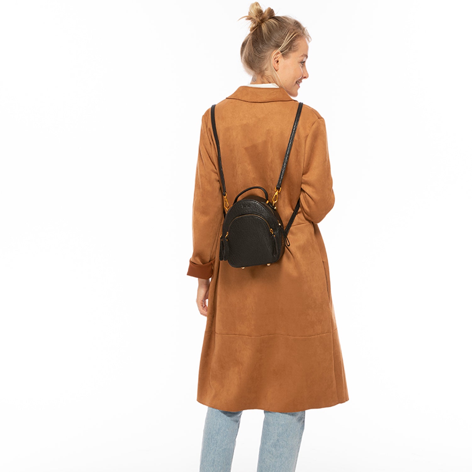 Woman wearing a brown coat and carrying a black backpack on a white background
