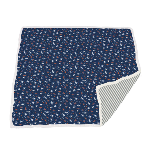 Floral patterned blanket with a striped reverse side on a white background