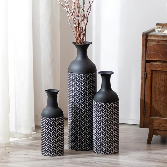 Set of three black metal floor vases in varying heights, featuring a matte black distressed finish and subtle woven texture, styled in a modern home setting.