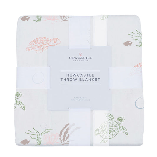 Folded bamboo muslin baby throw blanket with turtle and coral design.