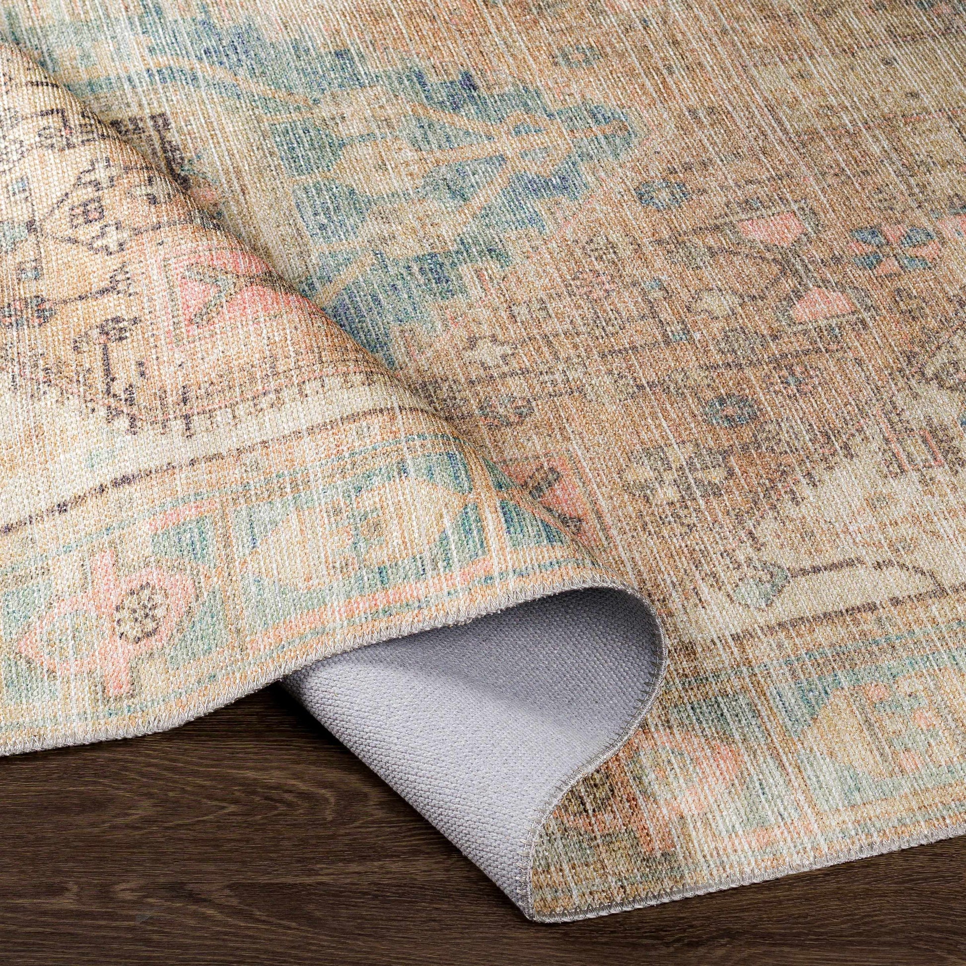 Close-up of a patterned rug with a textured border on a wooden floor.