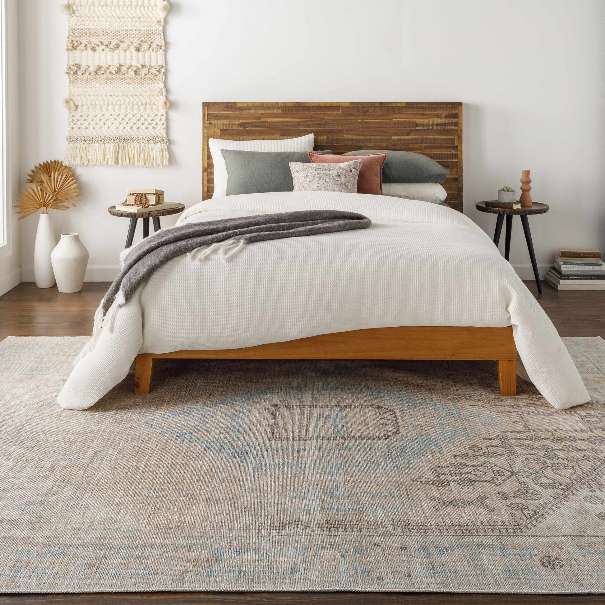 Bedroom with wooden bed, white bedding, and decorative pillows on a patterned rug.
