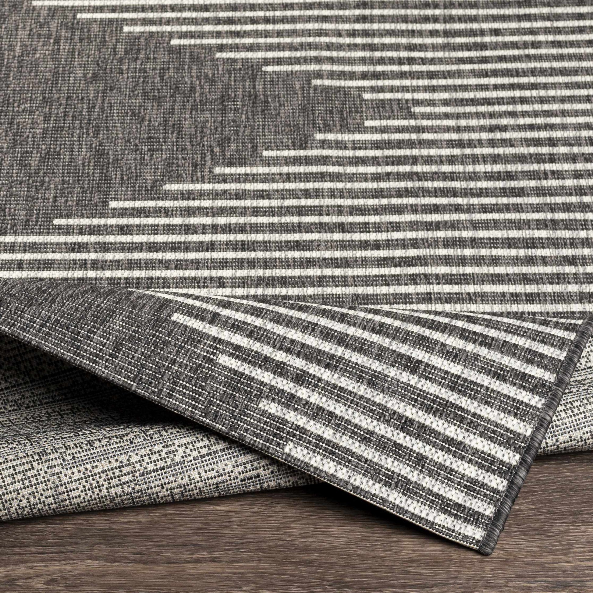 Stack of gray and white striped rugs on a wooden surface