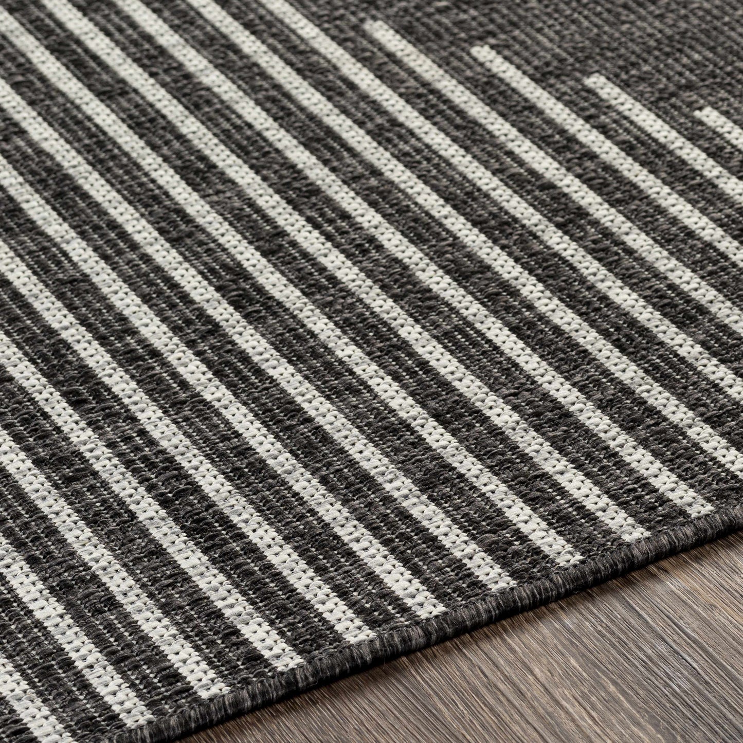 Close-up of a striped rug with black and white lines on a wooden floor.
