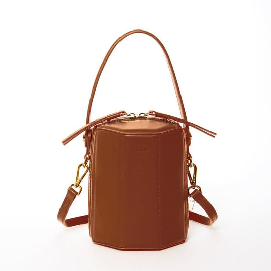 Harper amber brown leather bucket bag with gold hardware, featuring a unique geometric shape, teal interior, and a convertible carry design by SUSU.