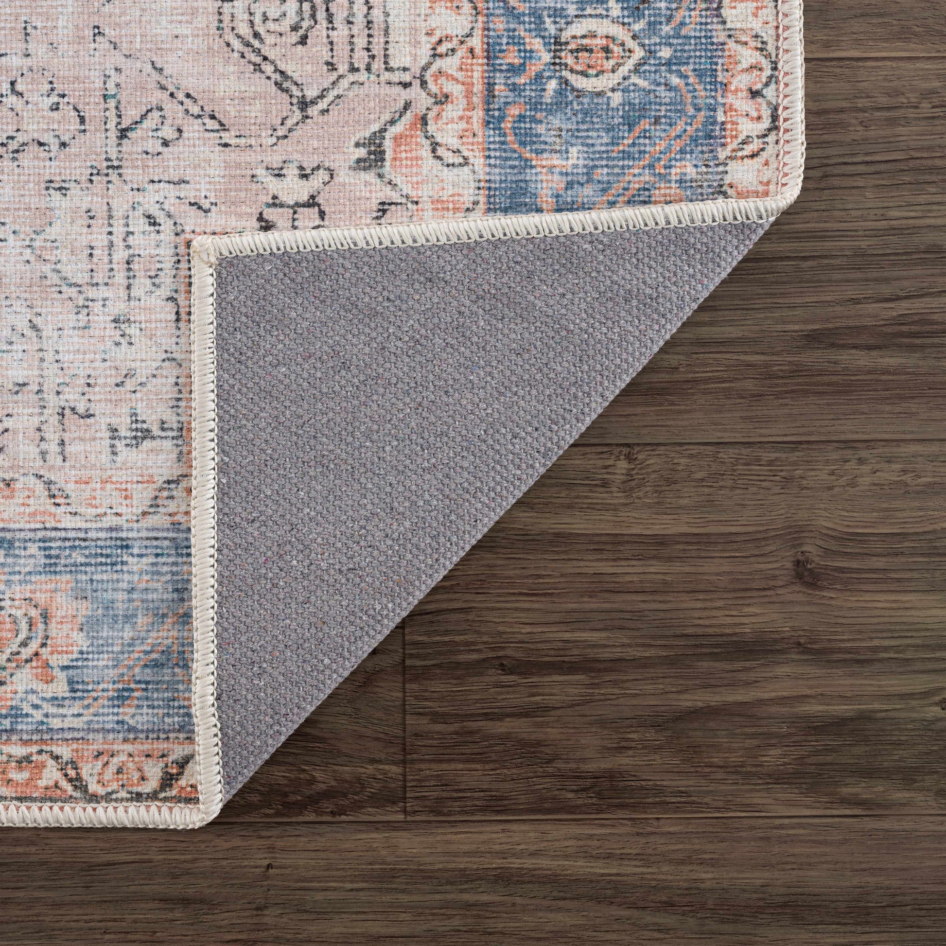 Corner of a patterned rug on a wooden floor
